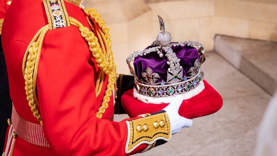 A member of the Royal Household is holding the Imperial State Crown.