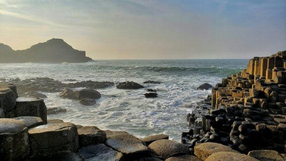 Image shows the Giant's Causeway in Northern Ireland and a view of the sea.