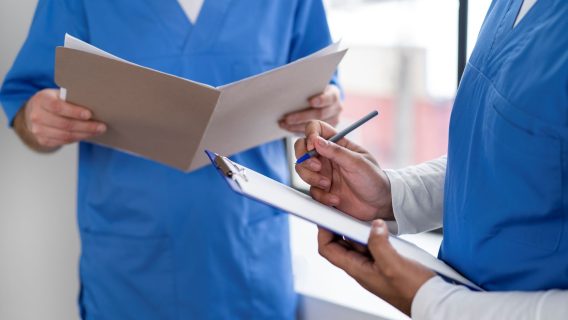 Shows nurses in blue scrubs holding documents